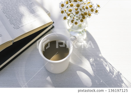 Morning with a white mug of coffee, a book and a vase Morning with a white mug of coffee, a book and a vase 136197125