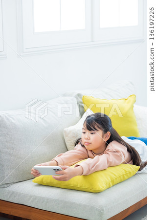 Elementary school girl playing with smartphone Elementary school girl playing with smartphone 136197226