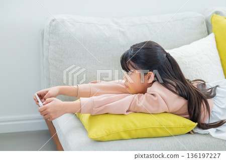 Elementary school girl playing with smartphone 136197227