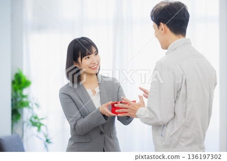 A woman giving a gift to a man in the office A woman giving a gift to a man in the office 136197302
