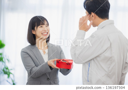 辦公室裡，一位女士送給一位男士一份禮物。 136197304
