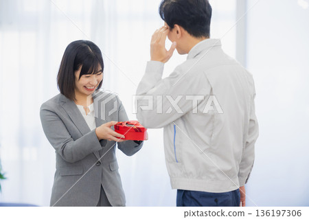A woman giving a gift to a man in the office A woman giving a gift to a man in the office 136197306