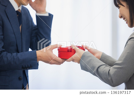 A woman giving a gift to a man in the office 136197317