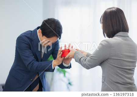 A woman giving a gift to a man in the office A woman giving a gift to a man in the office 136197318