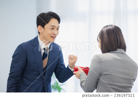 A woman giving a gift to a man in the office 136197321