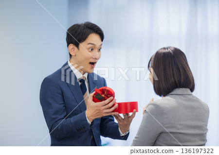 辦公室裡,一位女士送給一位男士一份禮物。 辦公室裡,一位女士送給一位男士一份禮物。 136197322