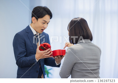 A woman giving a gift to a man in the office A woman giving a gift to a man in the office 136197323