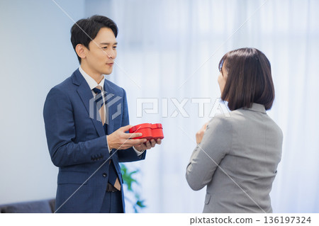 辦公室裡,一位女士送給一位男士一份禮物。 辦公室裡,一位女士送給一位男士一份禮物。 136197324