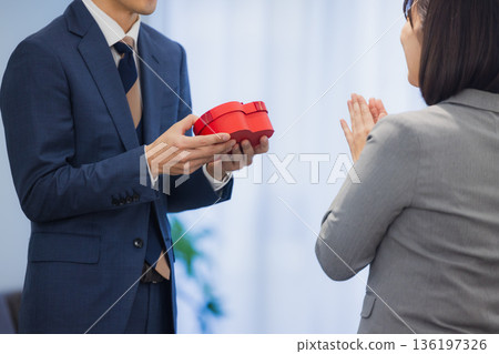辦公室裡，一位女士送給一位男士一份禮物。 136197326