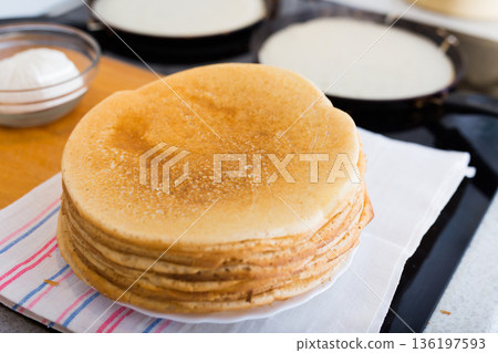 freshly baked hot cereal pancakes on plate and pans during cooking 136197593