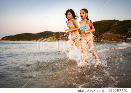 Two girls running splashing water on Greece beach 136197891