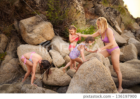 Mother and daughters enjoying summer climbing rocks in Greece Mother and daughters enjoying summer climbing rocks in Greece 136197900