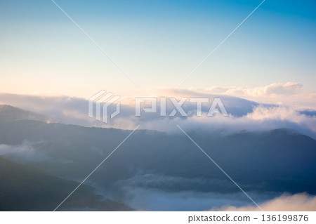 mountain landscape in fog. countryside spring scenery with cloudscape rolling above peaks. fantastic view in to the valley full of cold mist. perechyn highland of transcarpathia in forenoon light mountain landscape in fog. countryside spring scenery with cloudscape rolling above peaks. fantastic view in to the valley full of cold mist. perechyn highland of transcarpathia in forenoon light 136199876