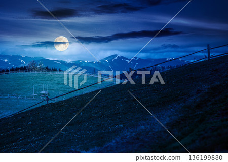 green rural landscape with wooden fence at night. countryside scene with rolling hill in spring in full moon light. pastoral highland region on cloudy weather. background for fake news or conspiracy green rural landscape with wooden fence at night. countryside scene with rolling hill in spring in full moon light. pastoral highland region on cloudy weather. background for fake news or conspiracy 136199880