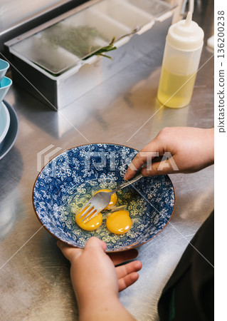 Beating eggs in bowl for cooking breakfast 136200238