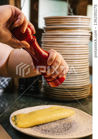 Grinding fresh pepper onto an omelet for breakfast 136200278