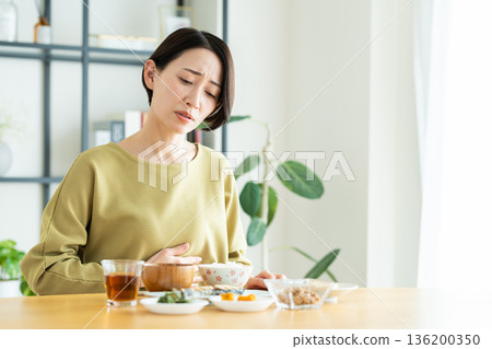 A middle-aged woman who has trouble eating A middle-aged woman who has trouble eating 136200350