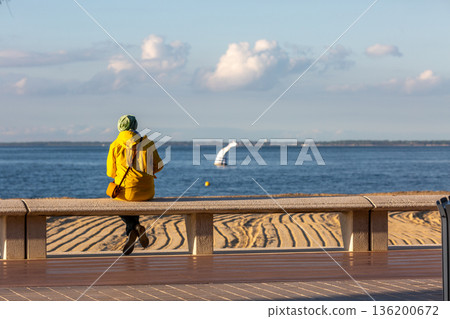 people sitting on a bench looking at the sea 136200672