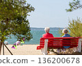 Back view of senior woman sitting on a bench at the beach 136200678