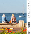 Back view of senior woman sitting on a bench at the beach 136200680