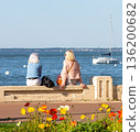 Back view of senior woman sitting on a bench at the beach 136200682