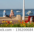 Back view of senior woman sitting on a bench at the beach 136200684