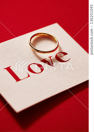 Engagement or wedding ring on a white card with carved love word, celebrating romance and Valentine's Day 136201045
