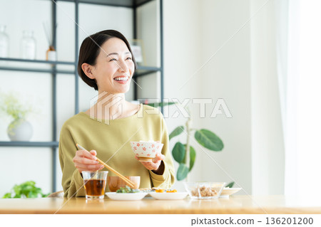 Middle-aged woman eating breakfast 136201200