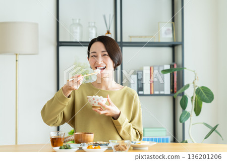 Middle-aged woman eating breakfast Middle-aged woman eating breakfast 136201206