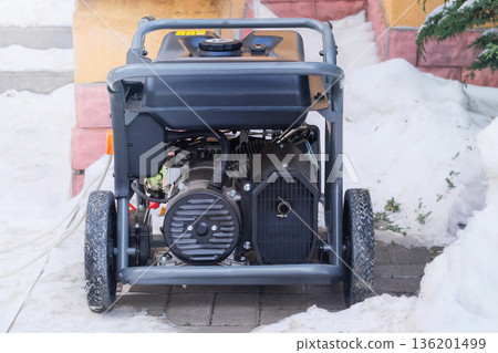 Power supply generator placed on street sidewalk. Mobile diesel generator is running outside in winter. Energy independence and electrical equipment. 136201499