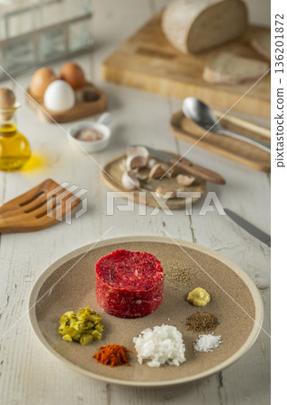 Preparing beef tartare with various ingredients on a plate Preparing beef tartare with various ingredients on a plate 136201872