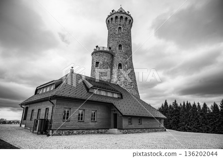 The Dalimil Lookout Tower stands tall on Vetrov Hill, showcasing its stone architecture under a dramatic cloudy sky in Czechia. Visitors explore the area near the tower's base. The Dalimil Lookout Tower stands tall on Vetrov Hill, showcasing its stone architecture under a dramatic cloudy sky in Czechia. Visitors explore the area near the tower's base. 136202044