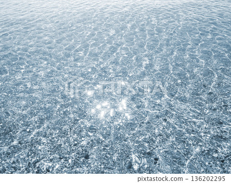 Clean transparent water on shallow sandy seashore with shells with shells on sunny summer day. Sun glare on surface of water. Small waves on sea coast. Nature backdrop. Natural background Clean transparent water on shallow sandy seashore with shells with shells on sunny summer day. Sun glare on surface of water. Small waves on sea coast. Nature backdrop. Natural background 136202295