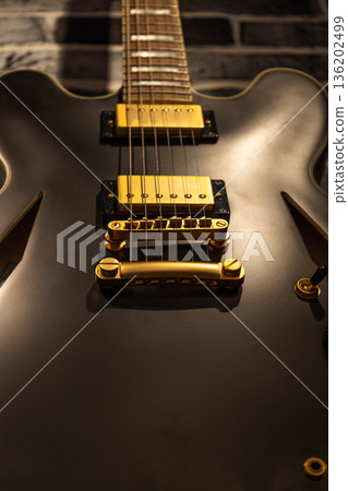 Close up of a matte black electric guitar with gold hardware 136202499