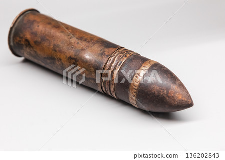 An old artillery shell of barrel artillery lies on white desk 136202843