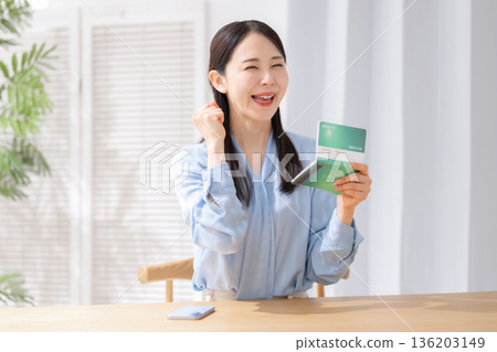 一名女子在存摺上揮舞著拳頭。 一名女子在存摺上揮舞著拳頭。 136203149