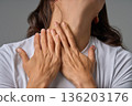 Close-up of woman touching her neck with both hands showing pain and discomfort 136203176