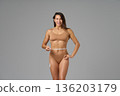Full-length portrait of fit woman measuring waist with tape showing confidence and body positivity 136203179