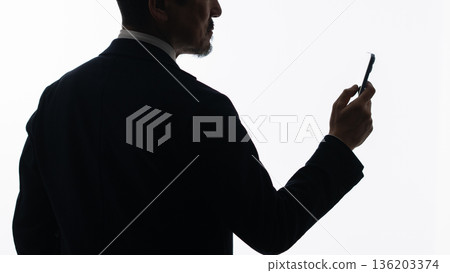 A businessman looking at a smartphone 136203374