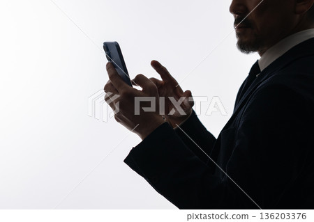 A businessman looking at a smartphone 136203376