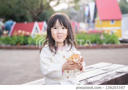 女孩在公園裡吃小吃 136203397
