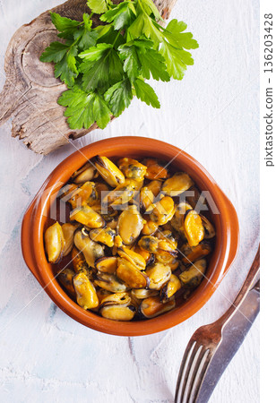 Mussels with sauce in a dish on a light background. 136203428