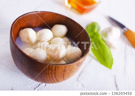 Tasty mozzarella balls and basil leaves in bowl Tasty mozzarella balls and basil leaves in bowl 136203450