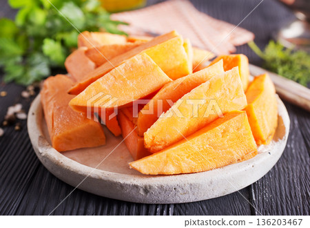 Fresh raw sweet potatoes, with fresh greens and salt on gray table Fresh raw sweet potatoes, with fresh greens and salt on gray table 136203467