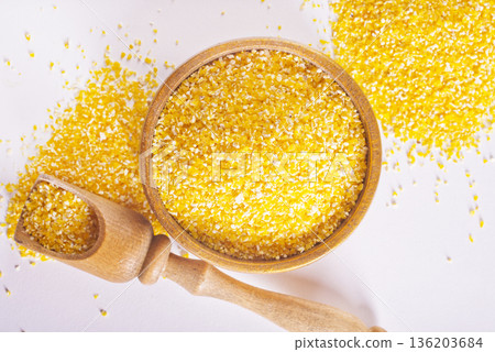 Raw cornmeal flour used in polenta, in wooden bowl 136203684
