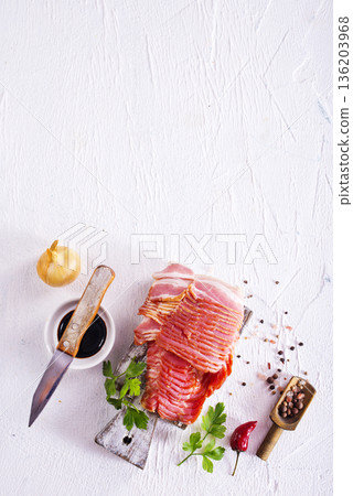 Fresh raw bacon sliced with spices and herbs on a lightr concrete background 136203968