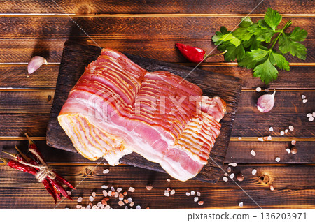 Fresh raw bacon sliced with spices and herbs on a dark concrete background 136203971