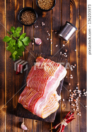 Fresh raw bacon sliced with spices and herbs on a dark concrete background 136203973