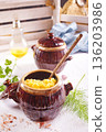 Corn porridge in a clay plate, a clay pot with porridge on a light background 136203986