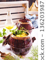 Corn porridge in a clay plate, a clay pot with porridge on a light background 136203987